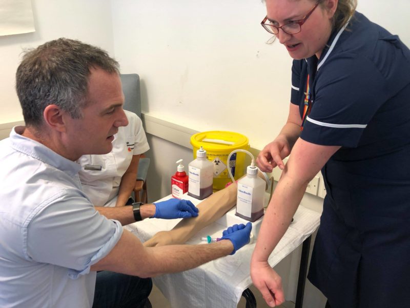Peter Kyle MP being taught how to take blood by trainee nurses at the University of Brighton