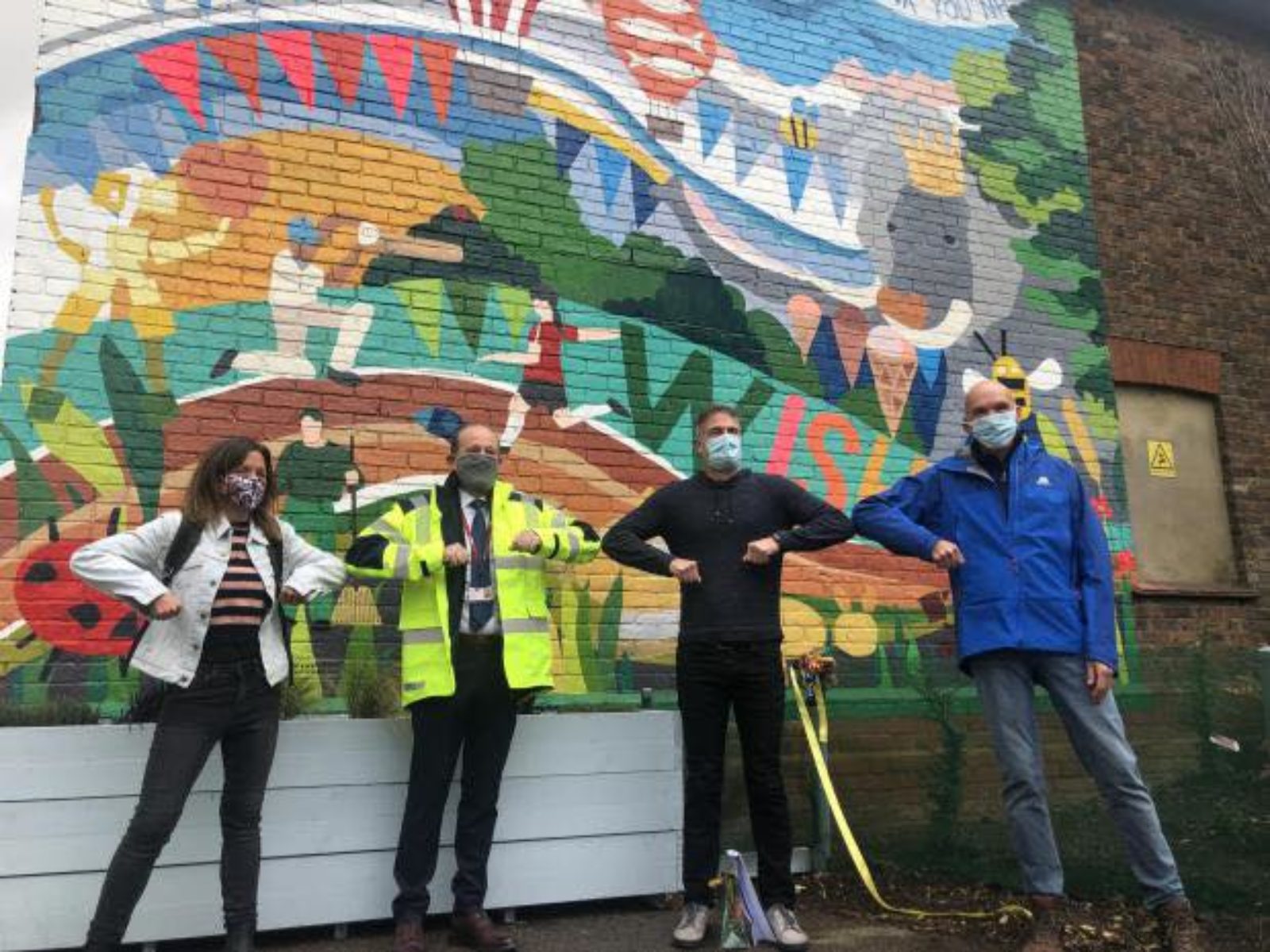 Peter Kyle and Wish Park representatives in front of a colourful mural located at Wish Park.