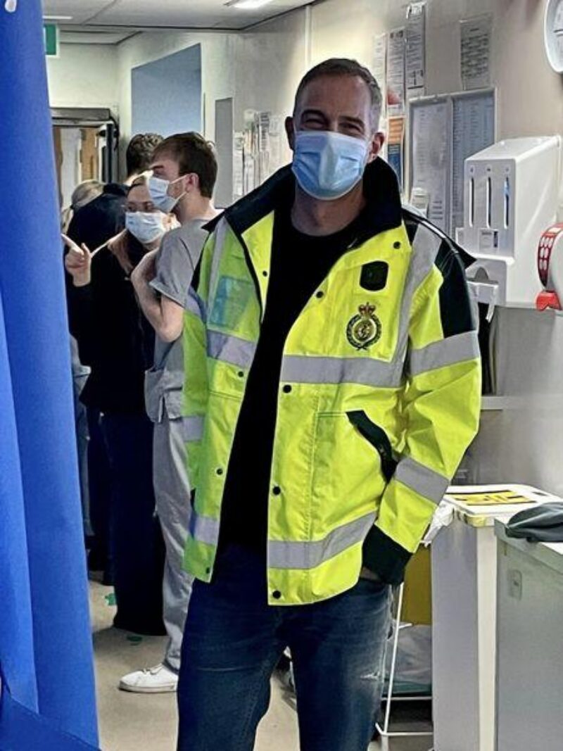 Peter stands in an A and E ward wearing a high visability coat
