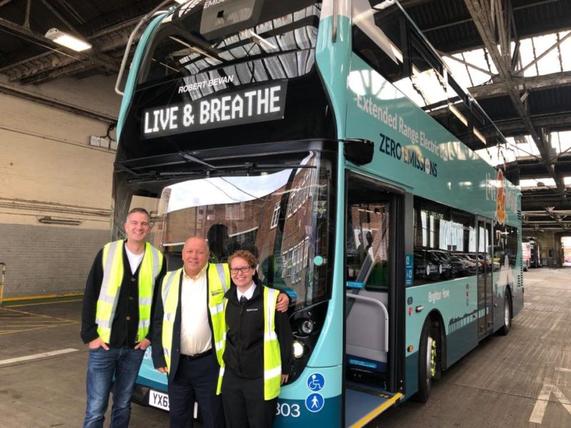 Peter stands with employees by a Brighton and Hove electric bus